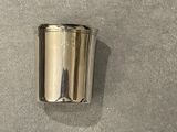 a silver cup sitting on a table next to a wall