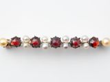 un gros plan sur une broche composée de perles rouges et blanches et de grenats