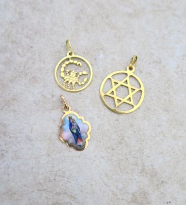 two gold pendants with religious symbols on them sitting on a table