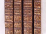 six vieux livres sont alignés sur une surface blanche
