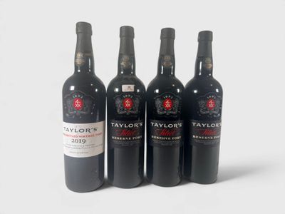 quatre bouteilles de vin sont alignées sur une surface blanche