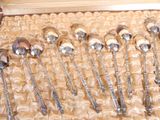 several silver spoons are lined up in a box on a table
