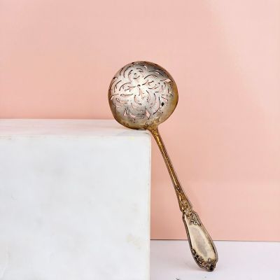 a gold spoon sitting on top of a marble block next to a pink wall
