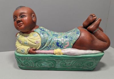 une figurine représentant un bébé allongé sur un plateau vert