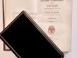 a black book sitting on top of a table next to an open book