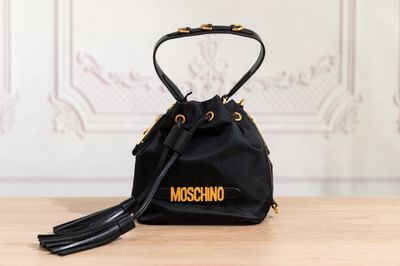un sac noir orné d'un logo doré, posé sur une table en bois