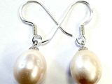 boucles d'oreilles argentées et perles blanches sur fond blanc
