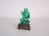 statue d'un homme assis sur un tabouret, tenant un livre