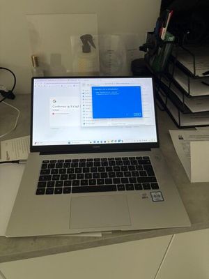 un ordinateur portable posé sur un bureau, devant une pile de livres