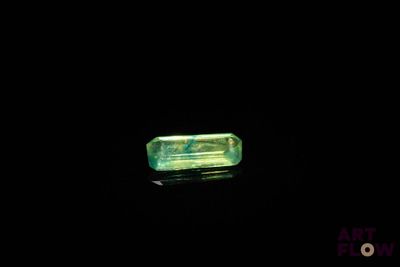 un gros plan d'un morceau de verre vert posé sur une surface noire