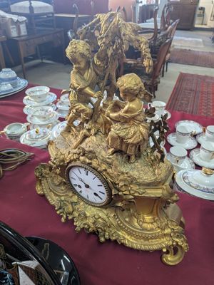 a gold clock sitting on a red table with a red table cloth