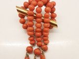 un gros plan sur un collier composé de perles orange et de pointes dorées