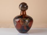 a brown and black vase sitting on a white table