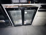 a refrigerator with two glass doors in the middle of a kitchen