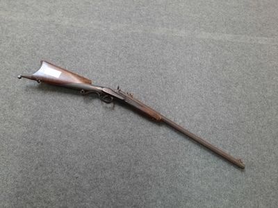 an old rifle with a wooden handle on a gray surface