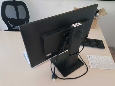 a computer monitor sitting on a desk with a keyboard and mouse