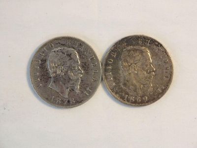 two silver coins sitting side by side on a white surface