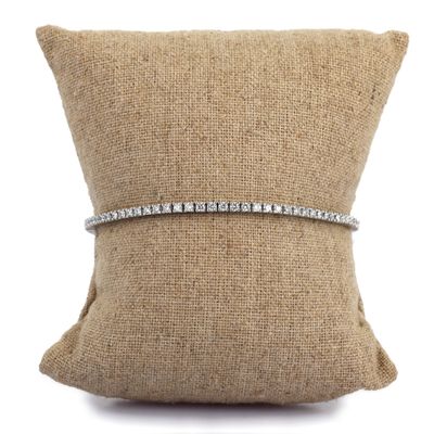 un bracelet en diamants posé sur un coussin, sur fond blanc