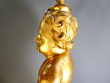 a gold statue of a child with a bird on top of it