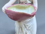 a figurine of a woman holding a large shell