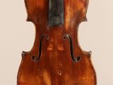 un vieux violon avec un fond en bois et un archet posé sur un support