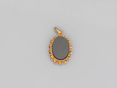 un pendentif en pierre dorée et noire sur fond blanc