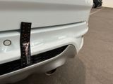 a sticker on the bumper of a white car that is parked in a parking lot