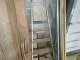 une échelle appuyée contre un mur, à côté d'un tas de bois
