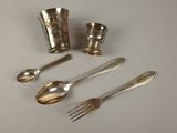 four silver spoons and two silver utensils on a table