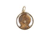 a close up of a gold plated pendant with a face in a circle
