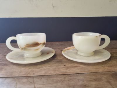 two cups and saucers sitting on a wooden table