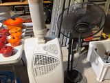 une pièce avec un ventilateur, une table et d'autres objets posés par terre
