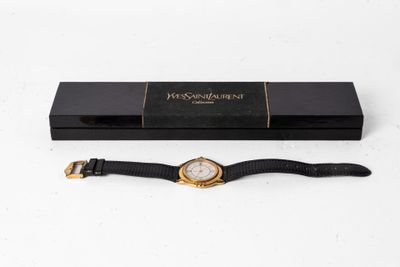 une montre noire et dorée avec un bracelet noir, présentée dans un coffret noir