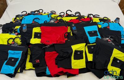 un lit sur lequel sont posés de nombreux pantalons