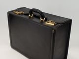 a black suitcase with a gold handle on a white surface
