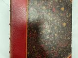 un vieux livre à la couverture rouge posé sur une surface blanche