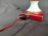 a white lamp with a red cord and a red book