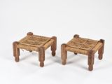 deux petits tabourets en bois avec des assises tressées, posés sur une surface blanche