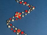 rosary necklace with red and white beads and a cross on a blue background