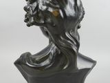 a bronze bust of a woman with long hair on a black base