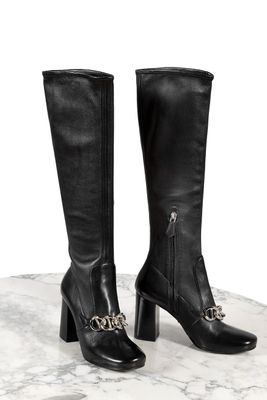 un gros plan sur une paire de bottes noires posées sur une surface en marbre