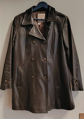 un manteau en cuir marron accroché au mur à côté d'un porte-manteau