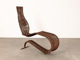 a brown wicker chair sitting on top of a cement floor