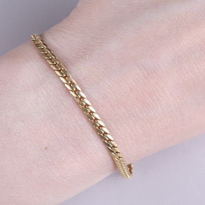 un gros plan sur la main d'une personne portant un bracelet en or