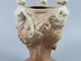 a vase that has a statue on the top of it