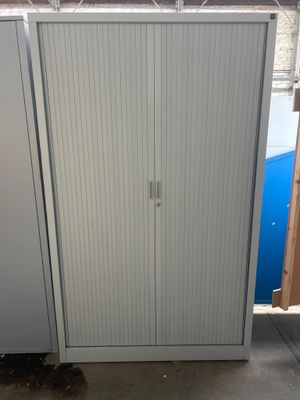 une armoire blanche avec une porte et une poubelle bleue à l'arrière-plan