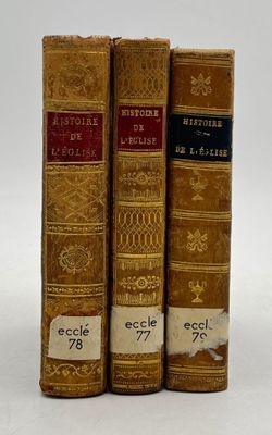 three old books are lined up on a white surface