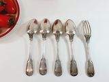 several spoons, forks, and a bowl of tomatoes on a table