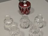 des bouteilles et des verres posés sur une table, avec un vase rouge en arrière-plan