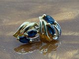 a gold ring with blue stones sitting on a wooden table